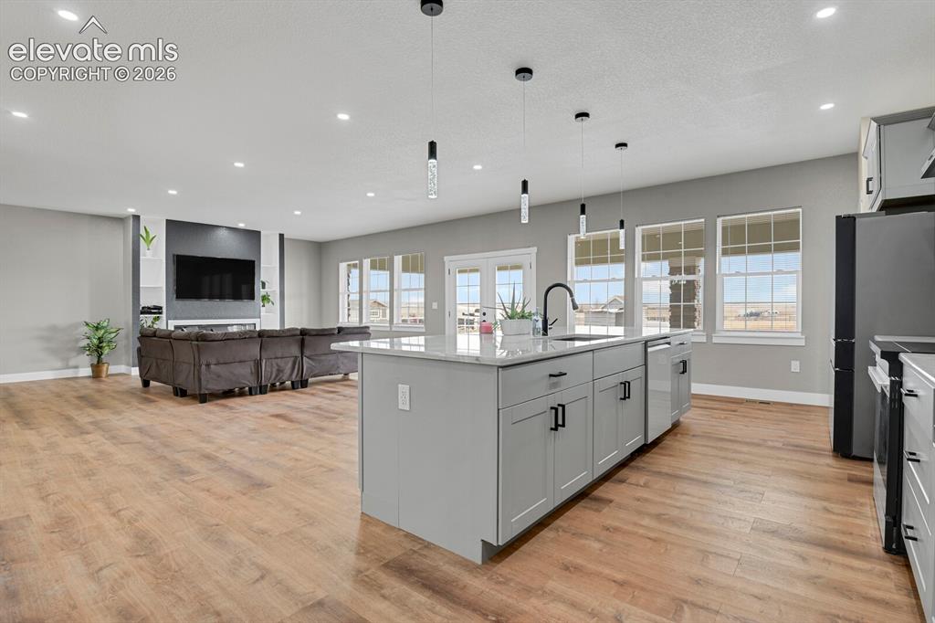 Image 20 of 49: Open-concept living space with wood-finish flooring, a kitchen island with
