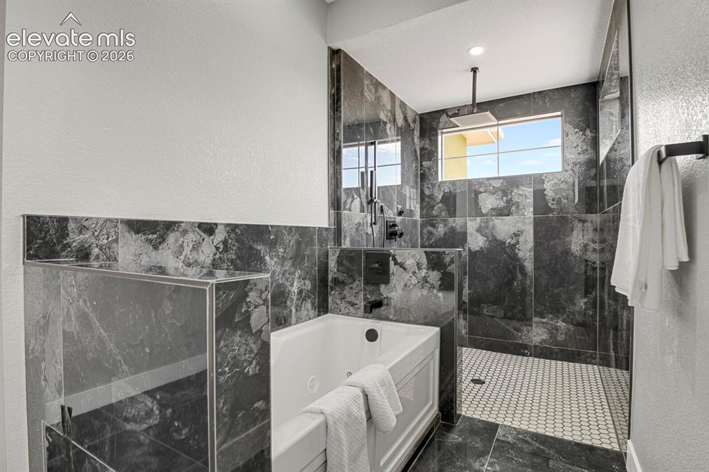 Image 32 of 49: Walk-in shower with a rainfall shower head, white hexagonal tile flooring,