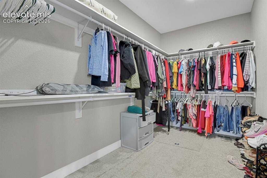 Image 33 of 49: Recessed ceiling lighting illuminates a walk-in closet featuring built-in s