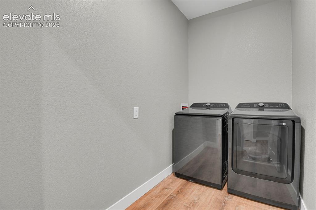 Image 34 of 49: Laundry area featuring wood-finish flooring and light-toned walls