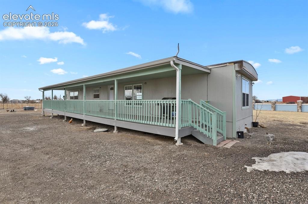 Image 35 of 49: Extended covered porch with railings and steps
