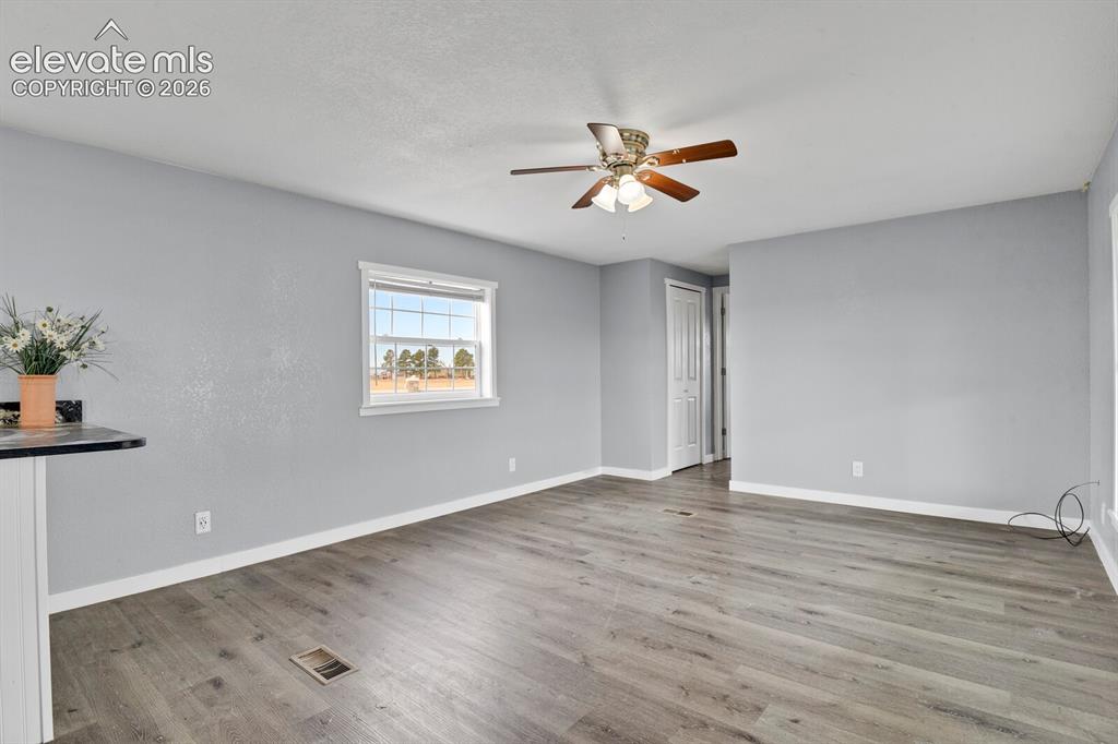 Image 37 of 49: Spacious room featuring wood-finish flooring, a ceiling fan with integrated