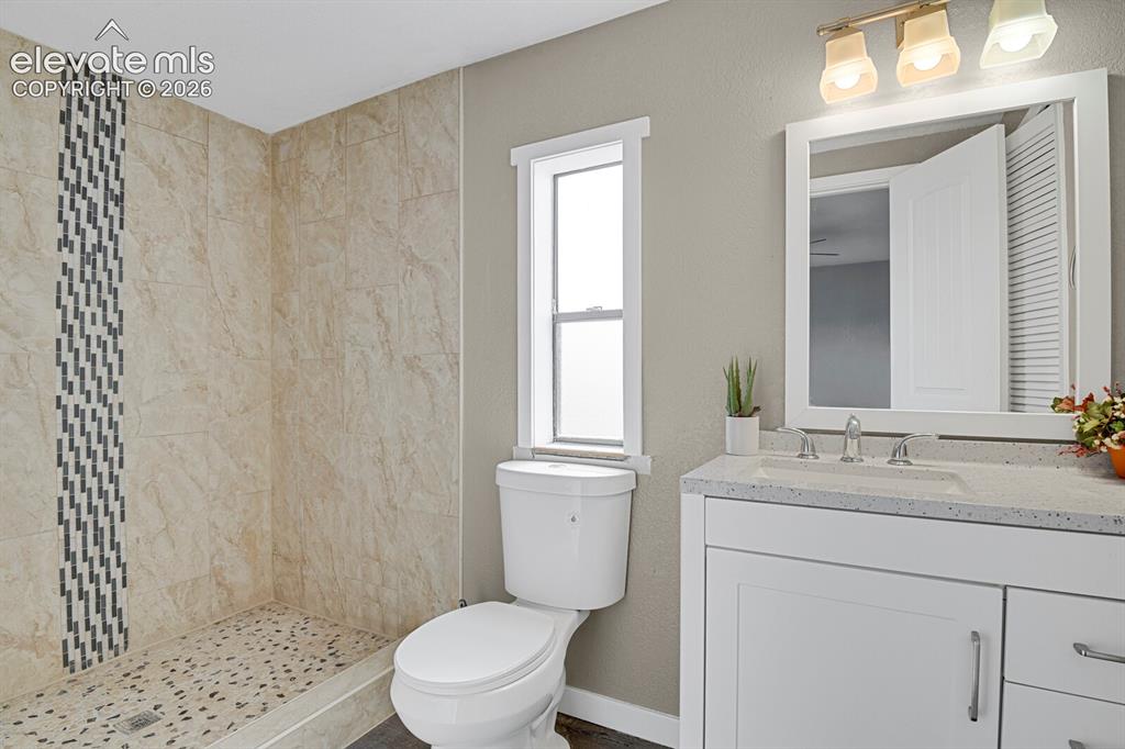 Image 41 of 49: Walk-in shower with natural stone-look tiling and mosaic accent, pebble sho
