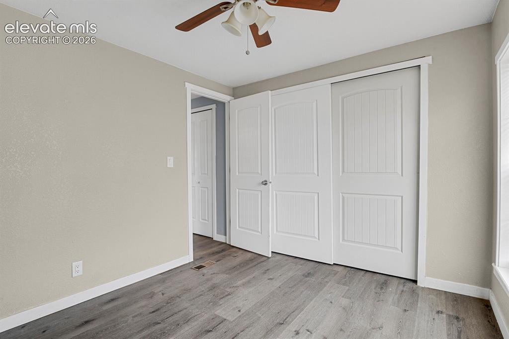 Image 42 of 49: Wood-finish flooring, white trim, sliding closet doors, ceiling fan, and wi