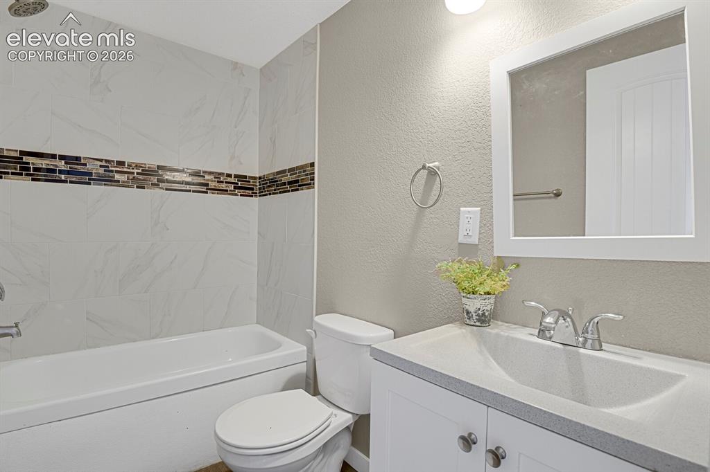 Image 43 of 49: White subway tile surround with a mosaic accent band, white bathtub, white
