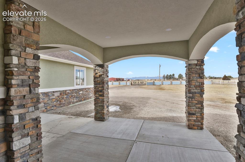 Image 46 of 49: Arched entryway featuring stone pillars and a concrete pad