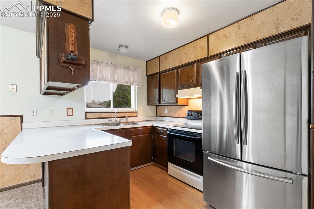 Image 24 of 45: Kitchen featuring freestanding refrigerator, range with electric stovetop,