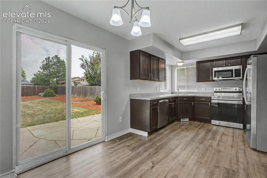 Image 10 of 18: Kitchen with wood-finish flooring, dark cabinetry, and light countertops