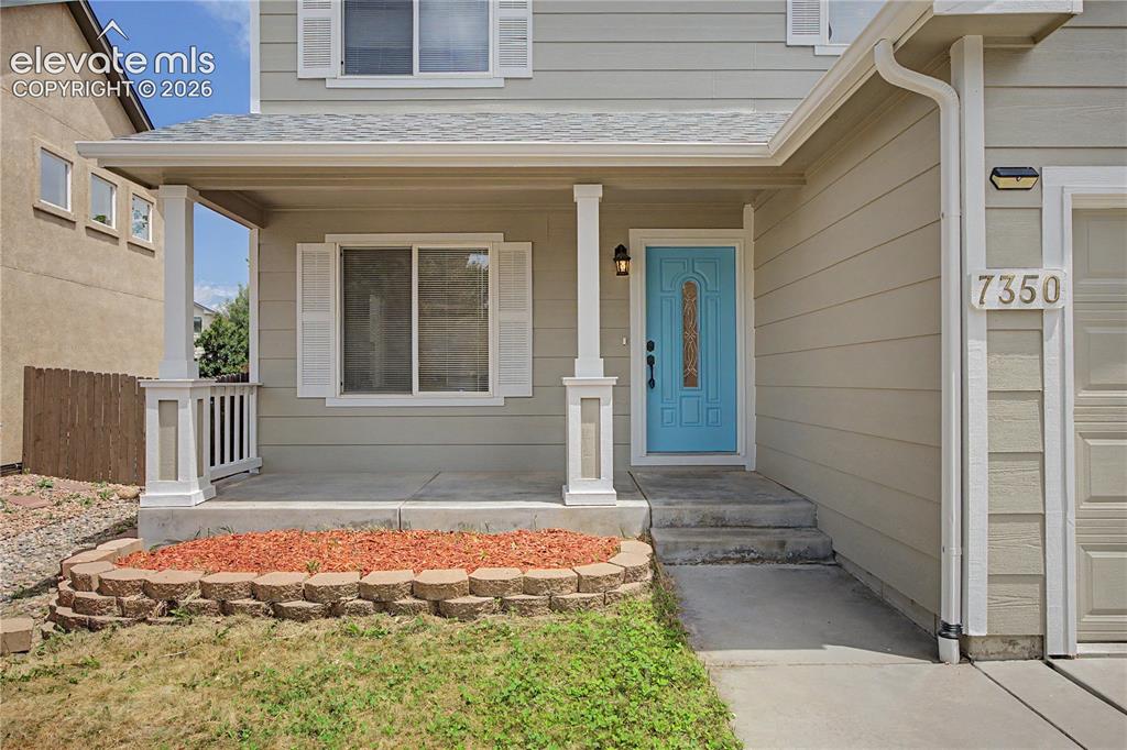 Image 14 of 18: Front exterior featuring a covered porch with white pillars and railing, a 