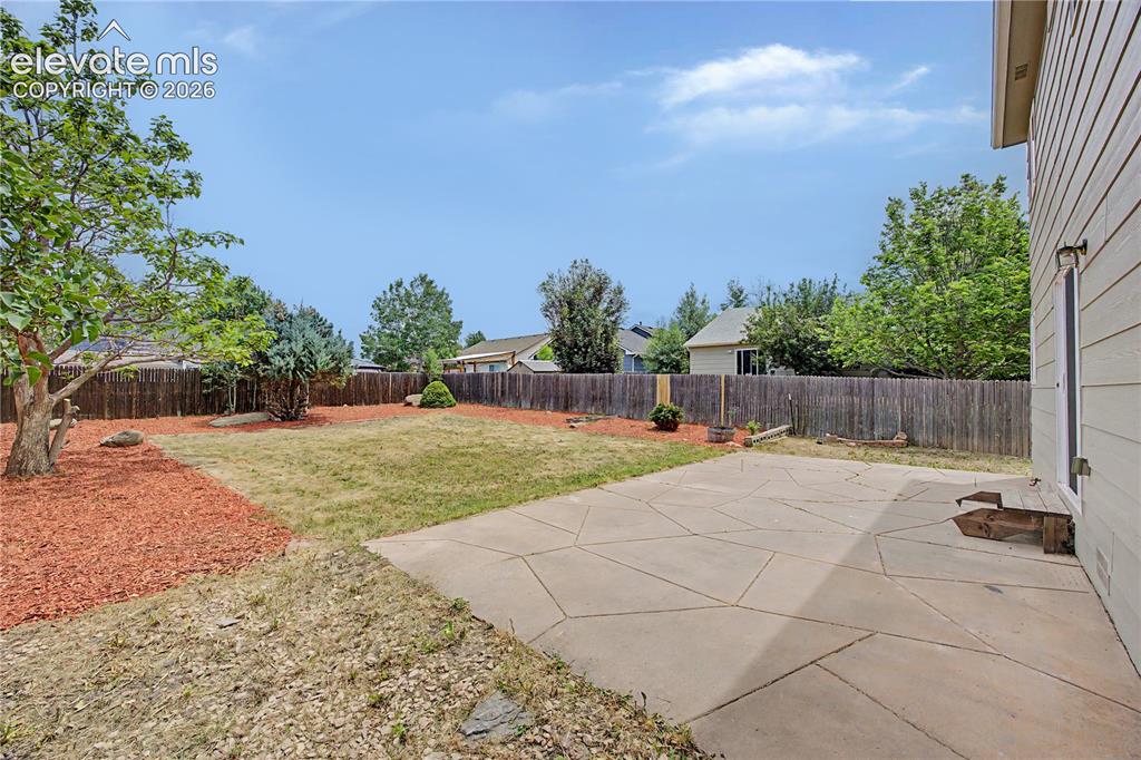 Image 17 of 18: Expansive backyard featuring a concrete patio with geometric scoring, wood 