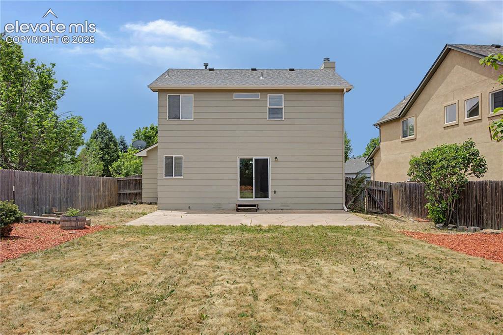 Image 18 of 18: Expansive backyard featuring a concrete patio, fenced perimeter, and a slid