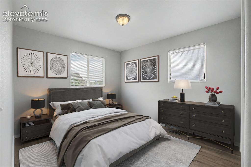 Image 6 of 18: Bedroom featuring wood-finish flooring, light gray wall paint, and multiple