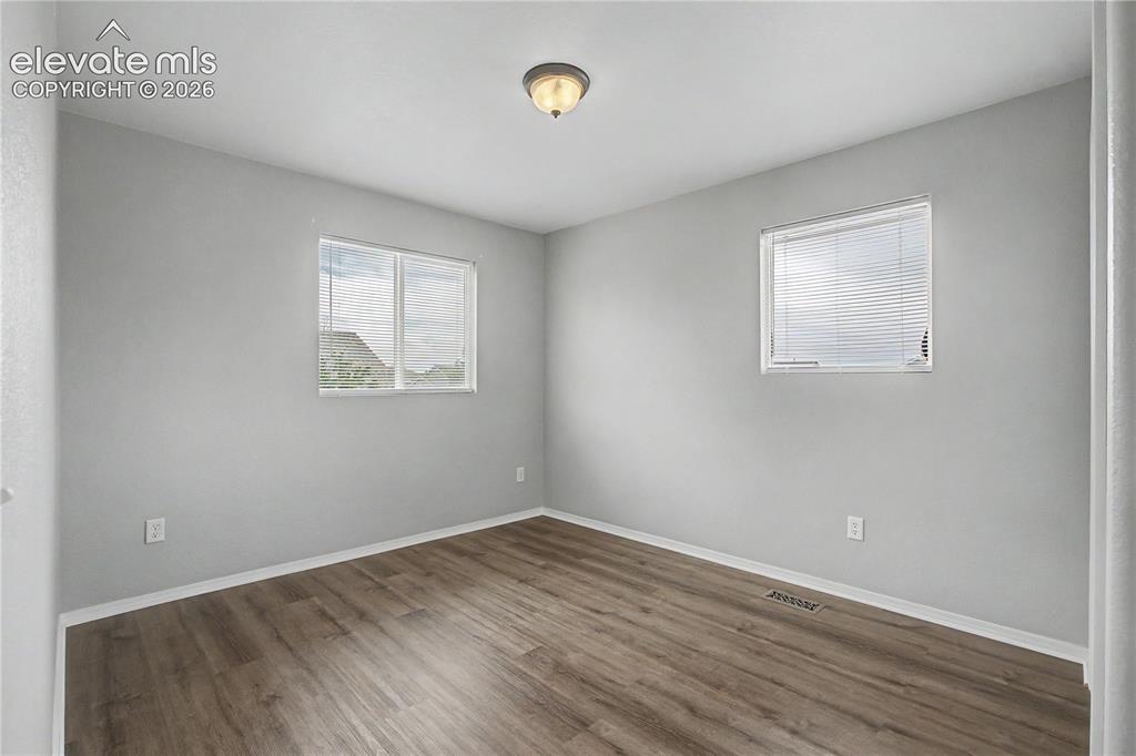 Image 7 of 18: Interior room featuring light gray walls, wood-finish flooring, white baseb