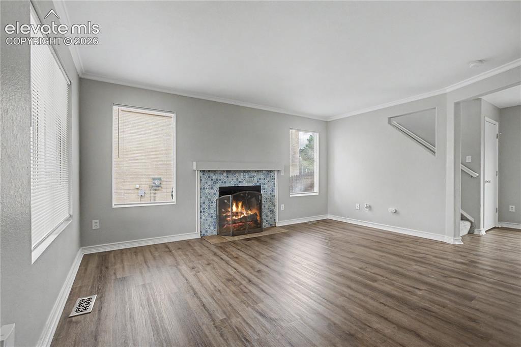 Image 9 of 18: Spacious living area featuring wide plank wood-finish flooring, a tile-surr