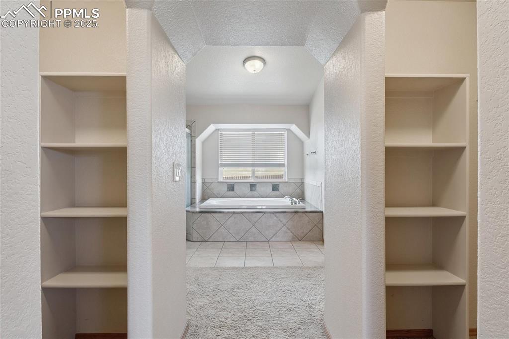 Image 23 of 42: His and hers closets looking towards primary bathroom 