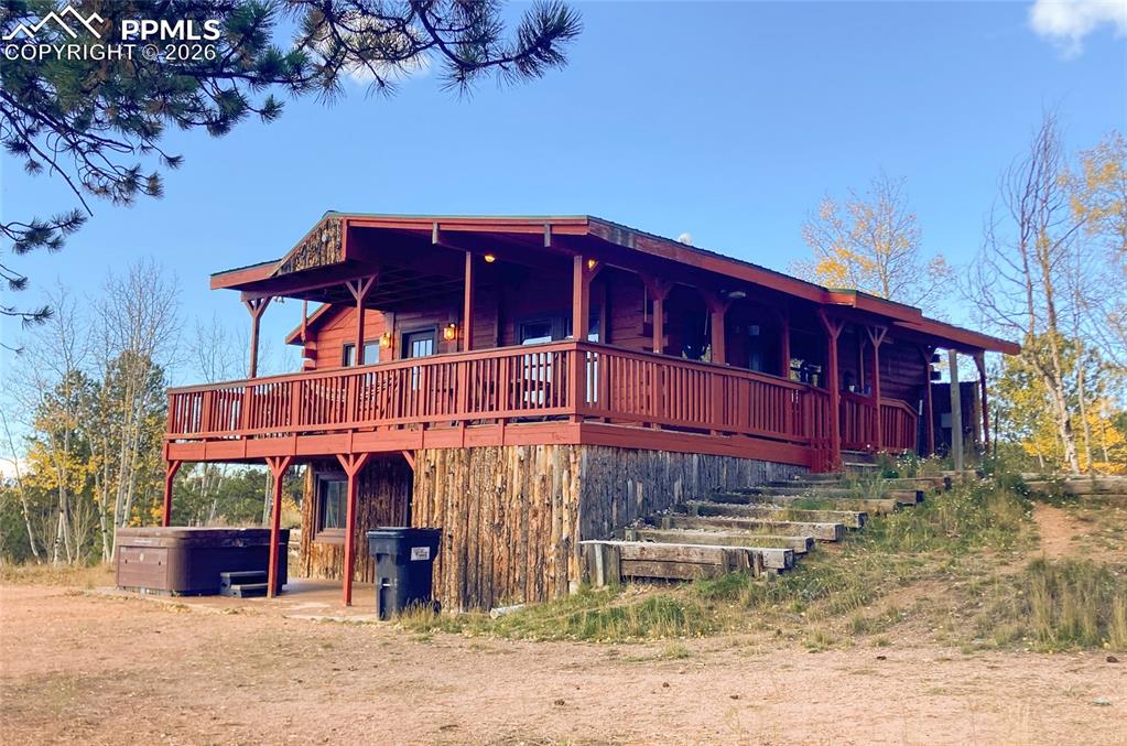 Caption: View of front of property featuring a hot tub, a large porch, and stairway