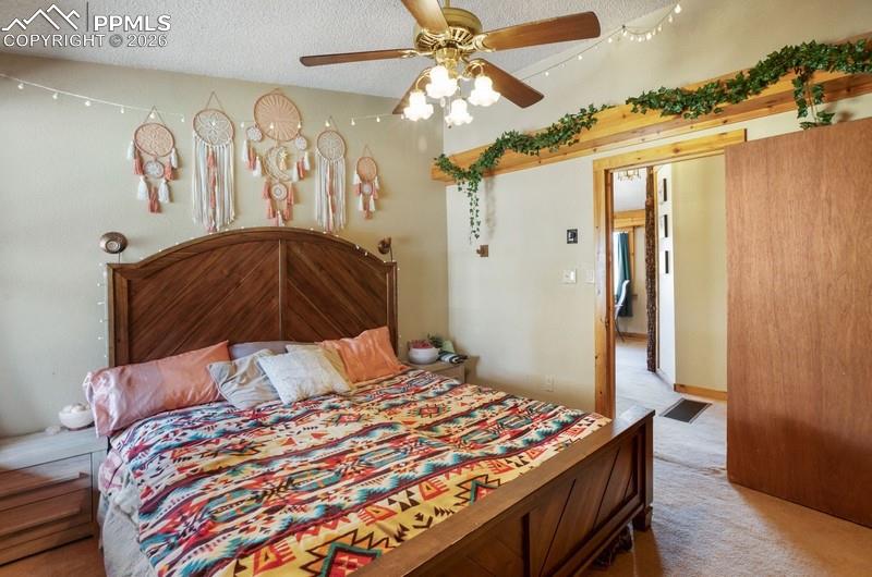 Image 13 of 32: Bedroom with carpet floors, a textured ceiling, and a ceiling fan