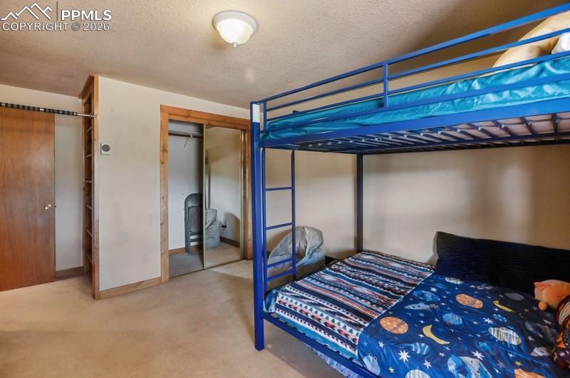 Image 18 of 32: Bedroom featuring carpet, a closet, a textured ceiling, and baseboards