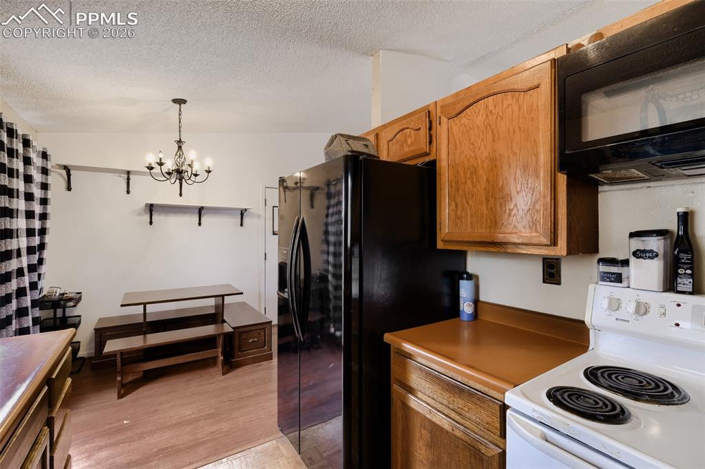 Image 12 of 28: Open-concept kitchen and dining area featuring wood-finish flooring, a pati