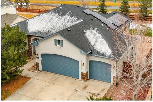 Caption: View of front of property featuring an attached garage, driveway, stone siding, and stucco siding