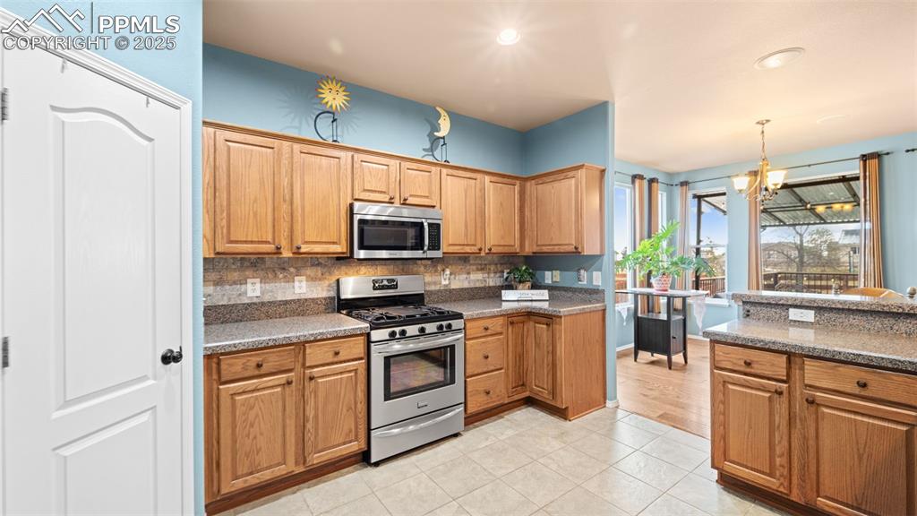 Image 11 of 42: Kitchen with appliances with stainless steel finishes, light stone countert