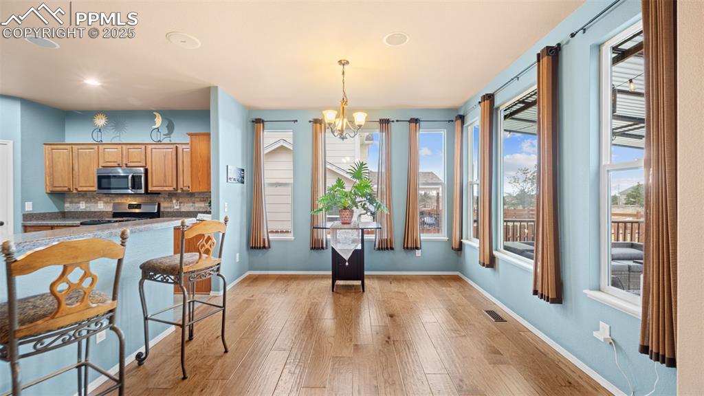 Image 13 of 42: Kitchen featuring a chandelier, backsplash, brown cabinetry, pendant lighti