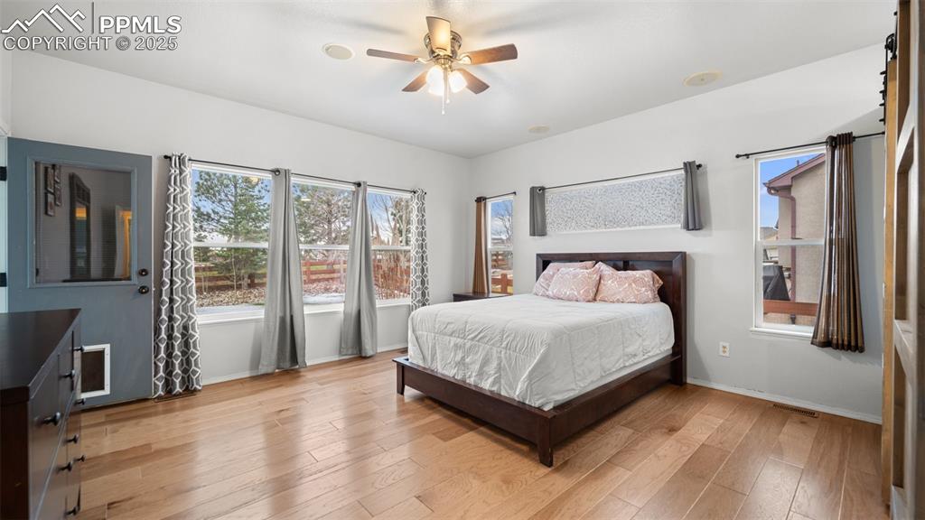 Image 18 of 42: Bedroom featuring light wood finished floors, ceiling fan, and multiple win