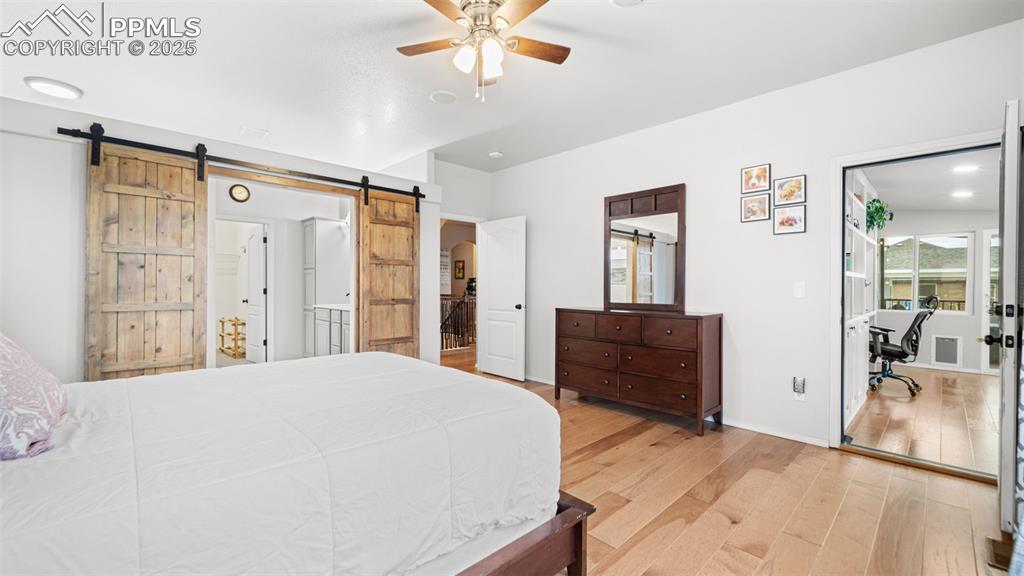 Image 20 of 42: Bedroom with light wood-style floors, ceiling fan, and an office area