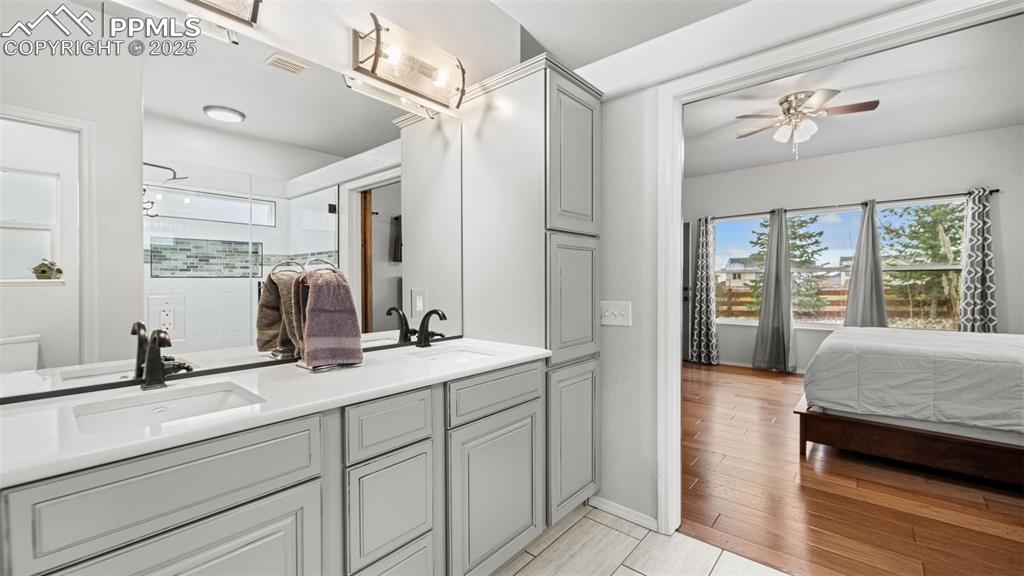 Image 23 of 42: Ensuite bathroom with double vanity, a stall shower, and ceiling fan