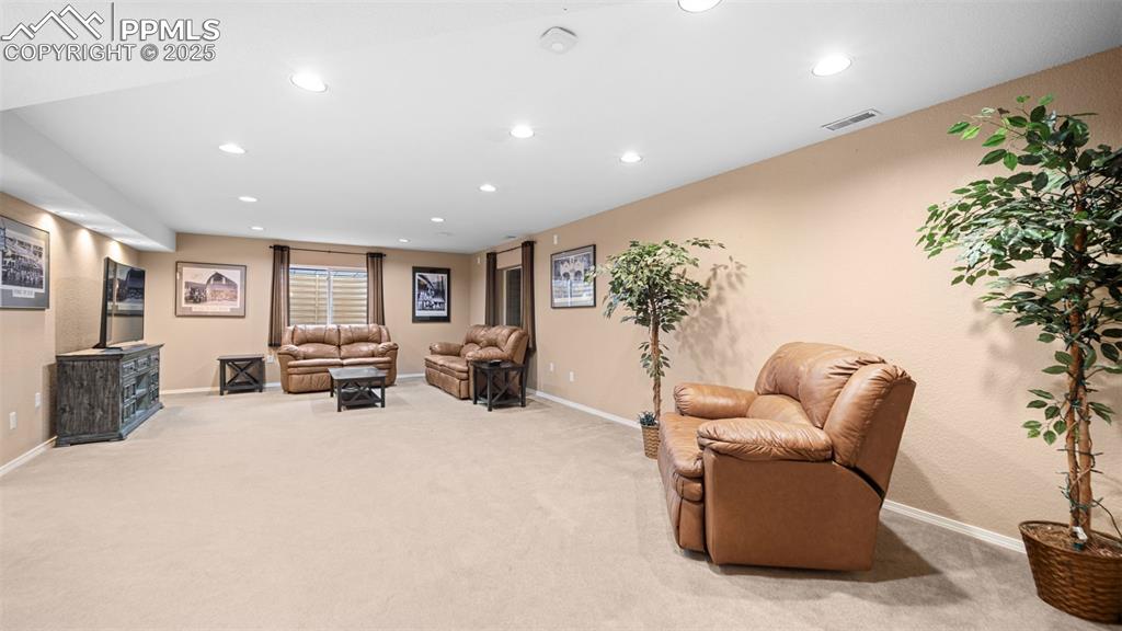 Image 27 of 42: Living area with recessed lighting and light carpet