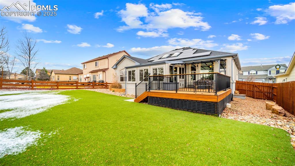 Image 33 of 42: Rear view of property with a fenced backyard, a deck, roof mounted solar pa