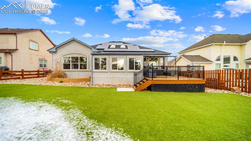 Image 34 of 42: Rear view of house featuring roof mounted solar panels, a fenced backyard, 