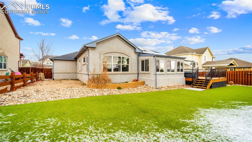 Image 35 of 42: Back of house featuring a fenced backyard, a wooden deck, and stucco siding