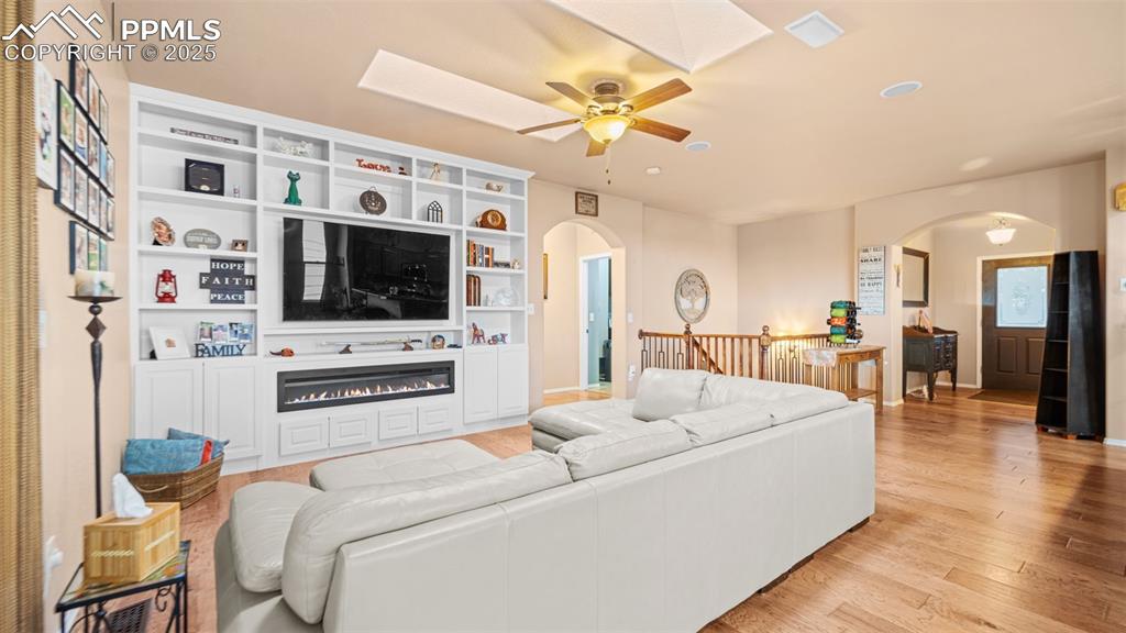 Image 8 of 42: Living area featuring light wood finished floors, a skylight, arched walkwa
