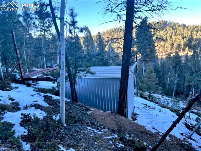 Image 8 of 21: Yard layered in snow with a view of trees and an outdoor structure