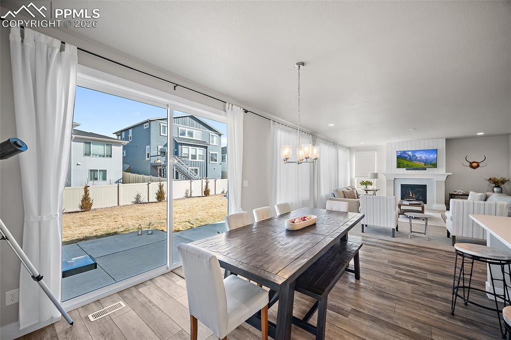 Image 10 of 45: Dining space with a lit fireplace, wood finished floors, plenty of natural 