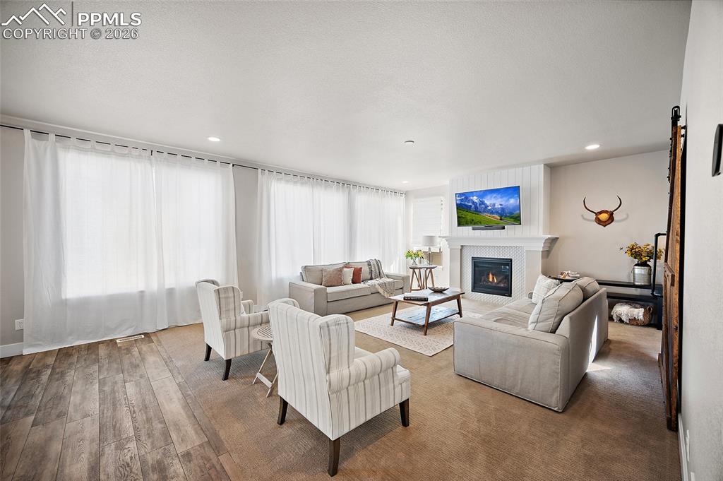 Image 11 of 45: Living area with a glass covered fireplace, wood finished floors, and reces