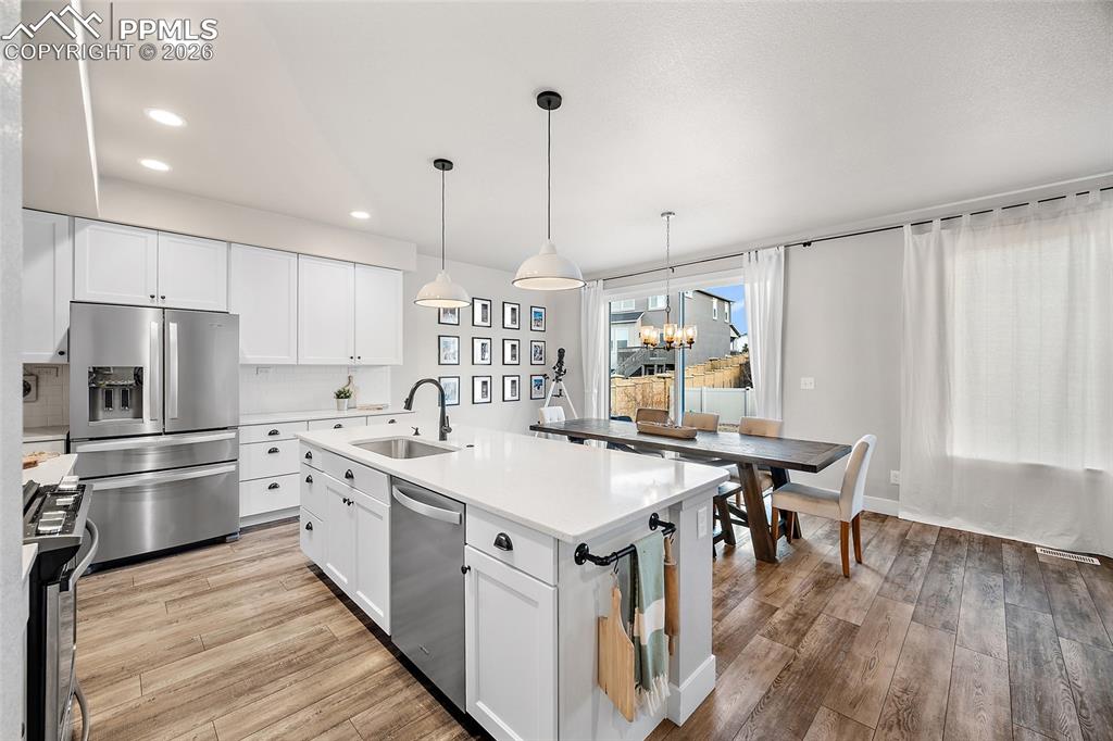 Image 6 of 45: Kitchen with stainless steel appliances, white cabinets, light wood-style f