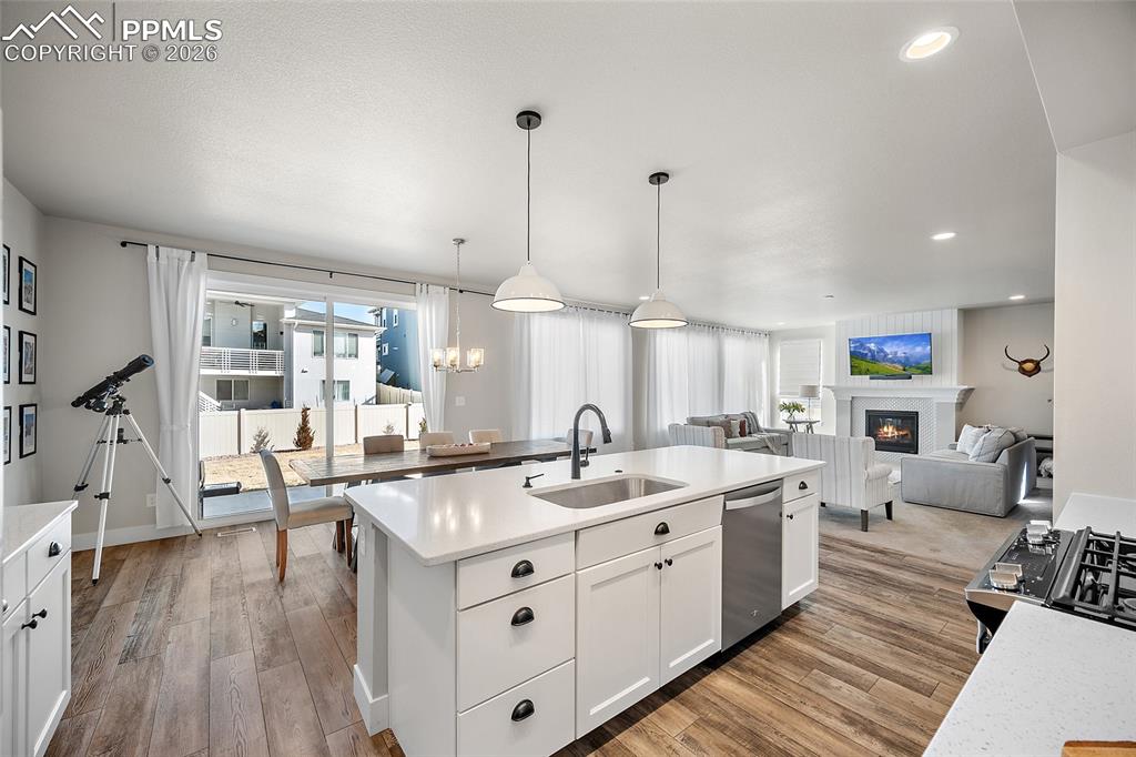 Image 8 of 45: Kitchen with a glass covered fireplace, open floor plan, light wood finishe