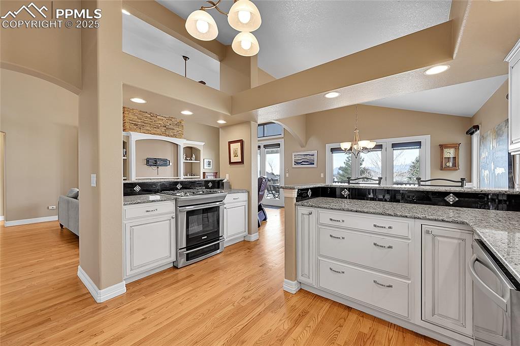Image 21 of 50: Kitchen with arched walkways, stainless steel appliances, white cabinetry,