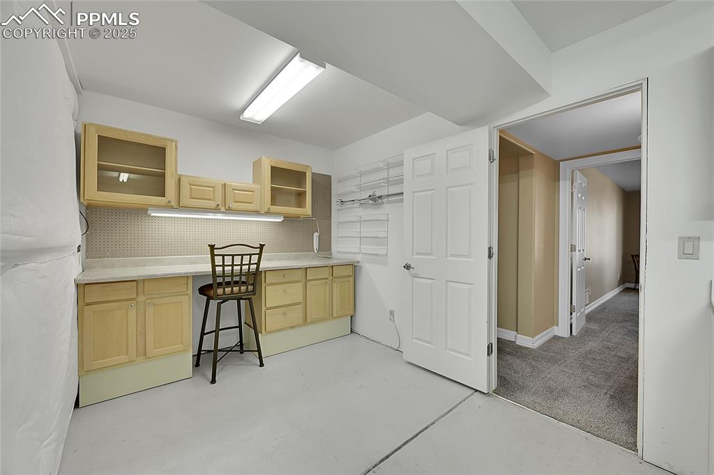 Image 47 of 50: Workshop/hobby area in basement featuring light brown cabinets, tasteful ba