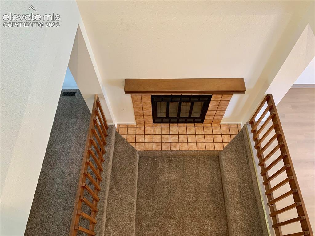 Image 10 of 18: Upstairs view of fireplace in living room.