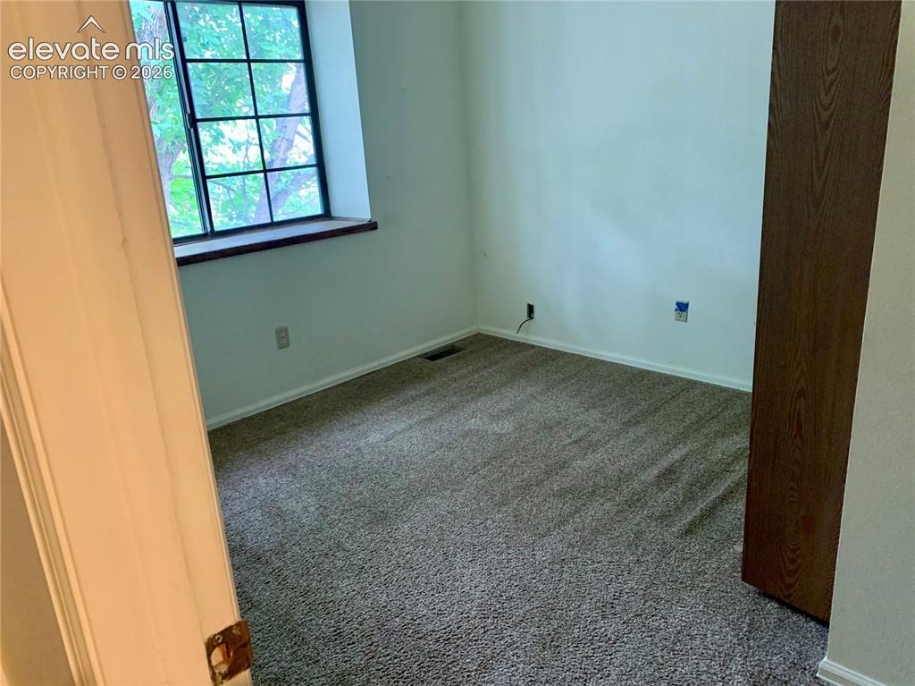 Image 11 of 18: Bedroom Carpeted flooring, white walls, and a window with dark framing