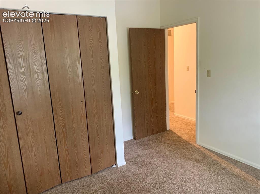 Image 13 of 18: Wood-finish bifold closet doors, light neutral wall color, and textured car
