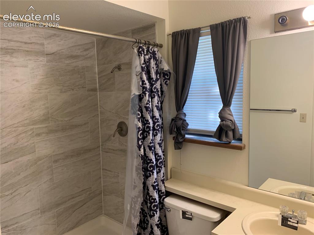 Image 19 of 27: Shower with light-toned rectangular tile surround and brushed bronze fixtur