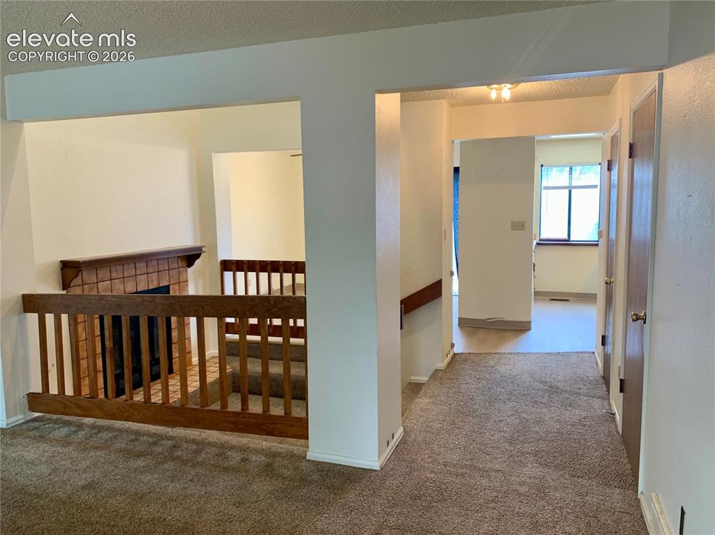 Image 2 of 18: Carpeted flooring, wood-finish railing, tile fireplace surround, wood-finis