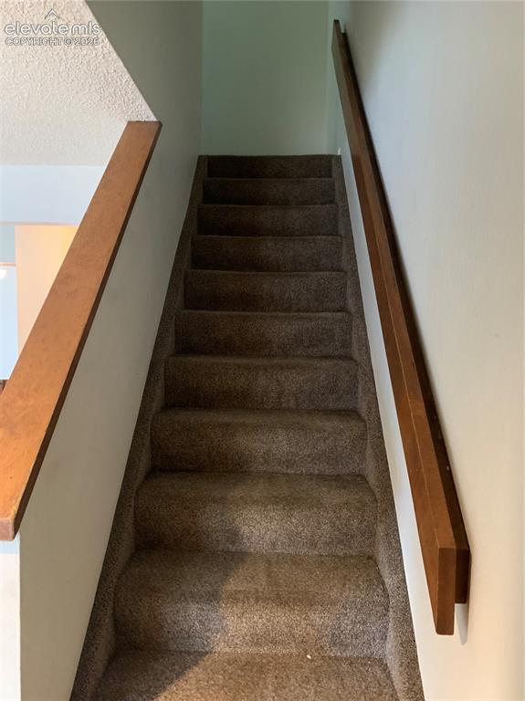 Image 20 of 27: Carpeted staircase with light-toned wall finishes and wood-finish handrails
