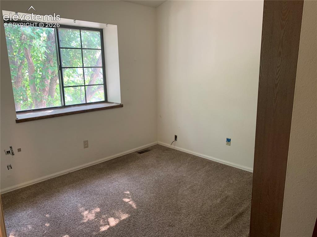Image 21 of 27: White-painted walls and a dark wood-finish trim accent a gridded window
