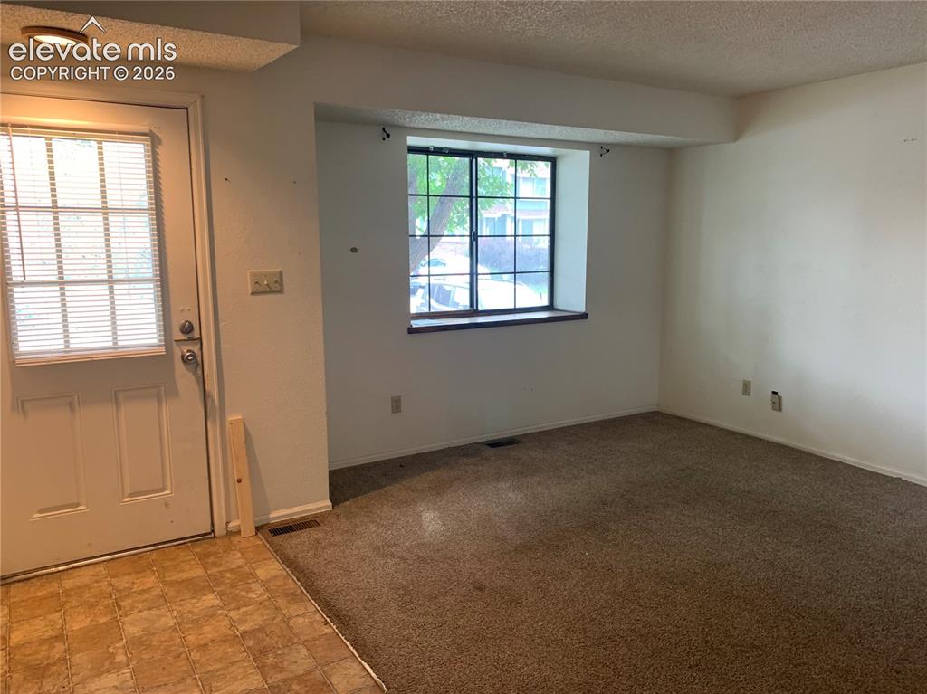 Image 7 of 27: Living room area and front door.