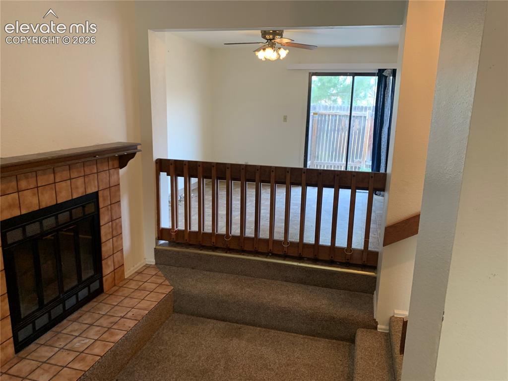 Image 8 of 27: Carpeted stairs leading to a living area featuring a terracotta-tiled firep
